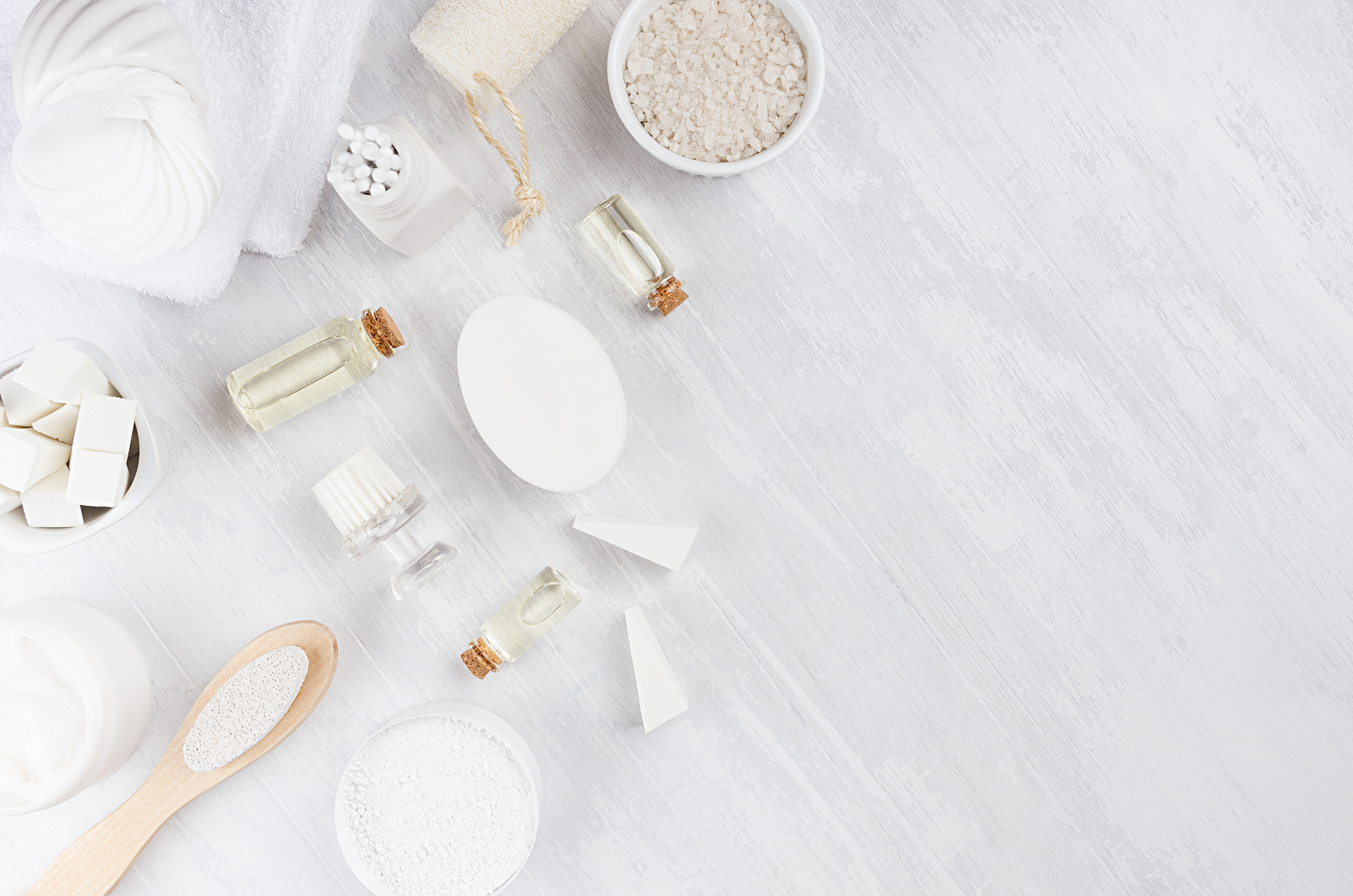 Delicate elegance light cosmetics products for body and skin care on white wood board, border, top view.